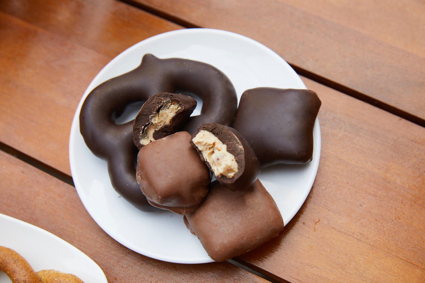 Chocolate-covered pretzels and snacks on a white plate