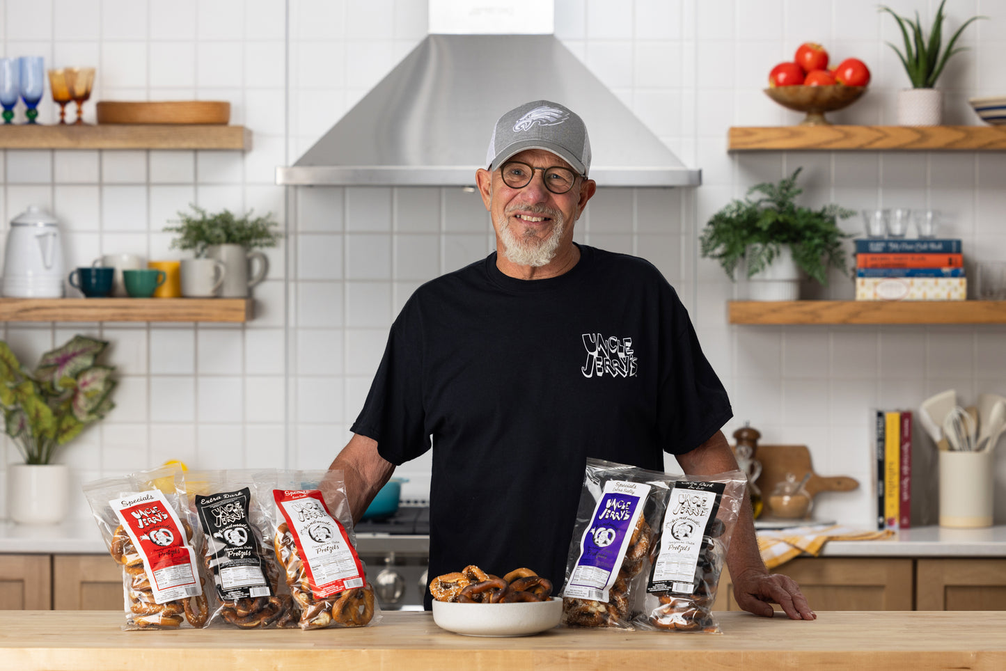 Smiling man in a kitchen standing behind Uncle Jerry’s pretzel bags